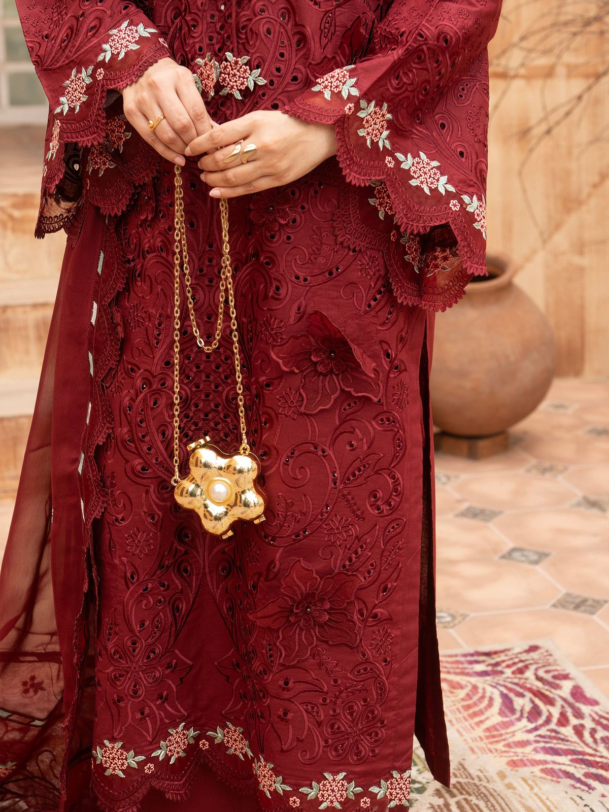Close-up of maroon embroidered lawn suit with gold chain bag